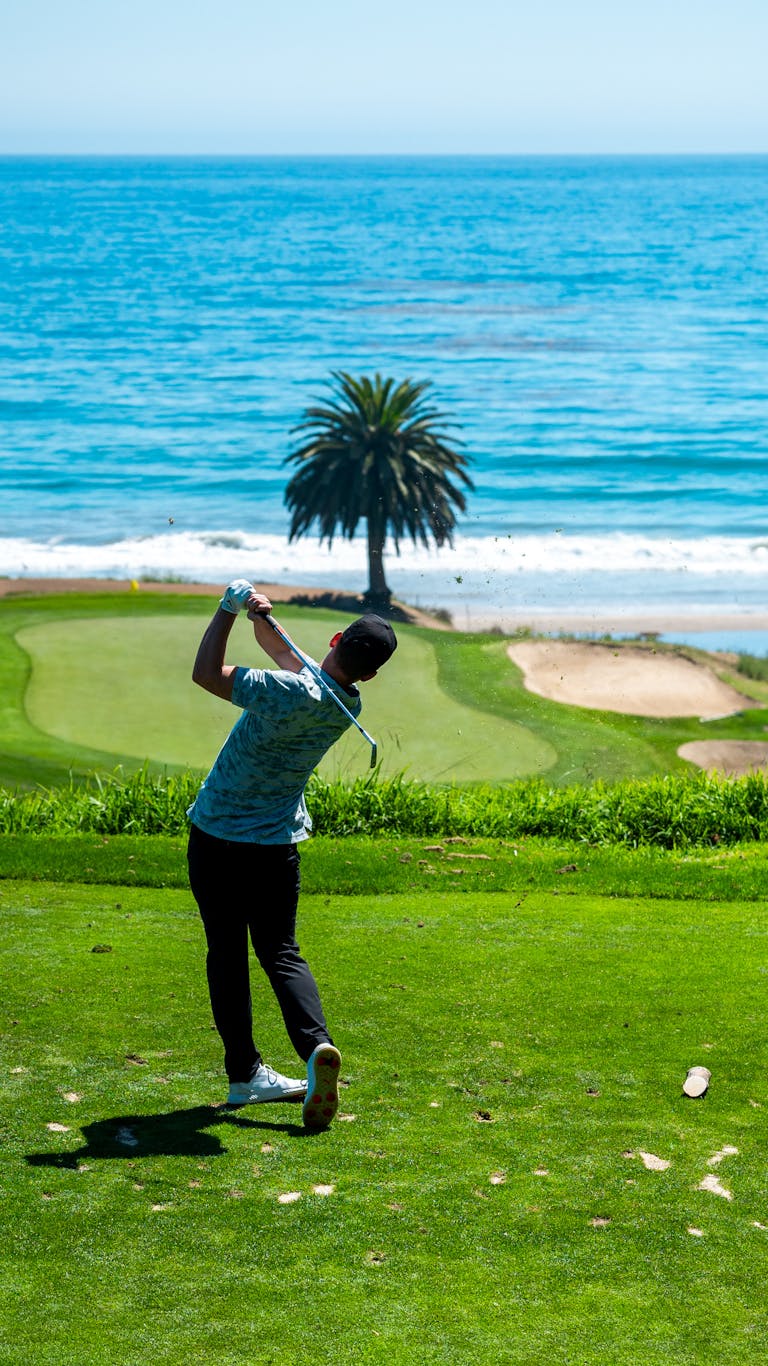 Golfer swinging on a picturesque golf course by the ocean in Santa Barbara, CA.