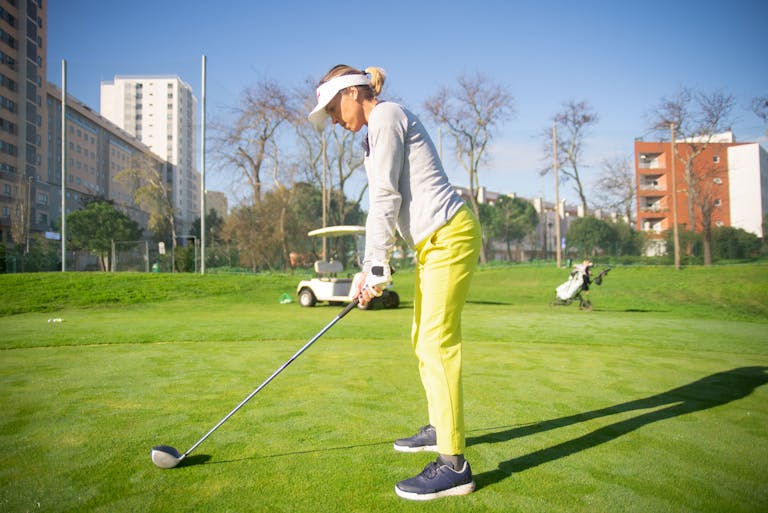 Woman practicing golf on a sunny day in Portugal, showcasing form and focus.